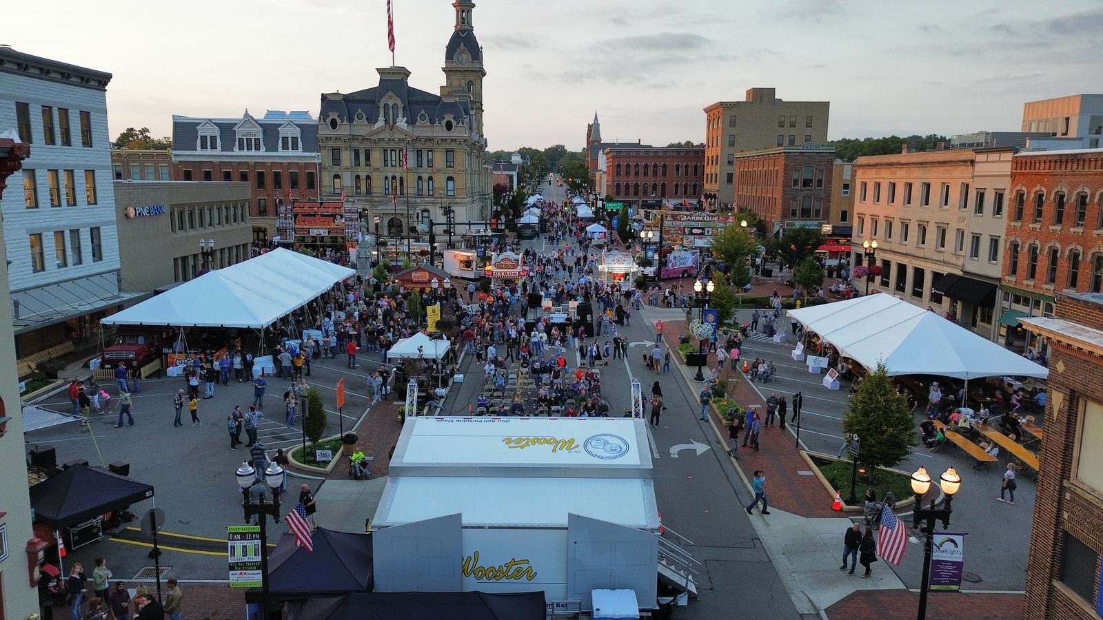 Downtown Wooster filled with people and tents during Woosterfest, the Wayne County courthouse at dusk